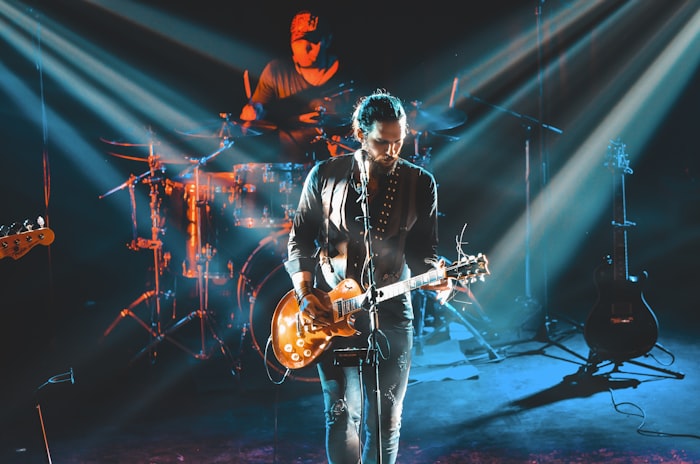 A guitarist performing on stage under dramatic lighting