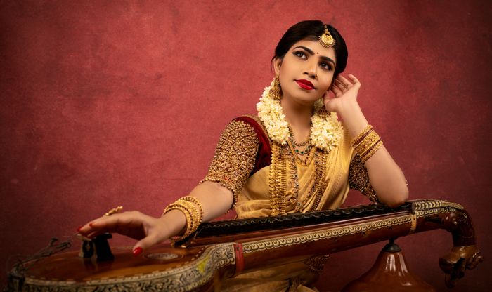 A woman in traditional attire playing a veena