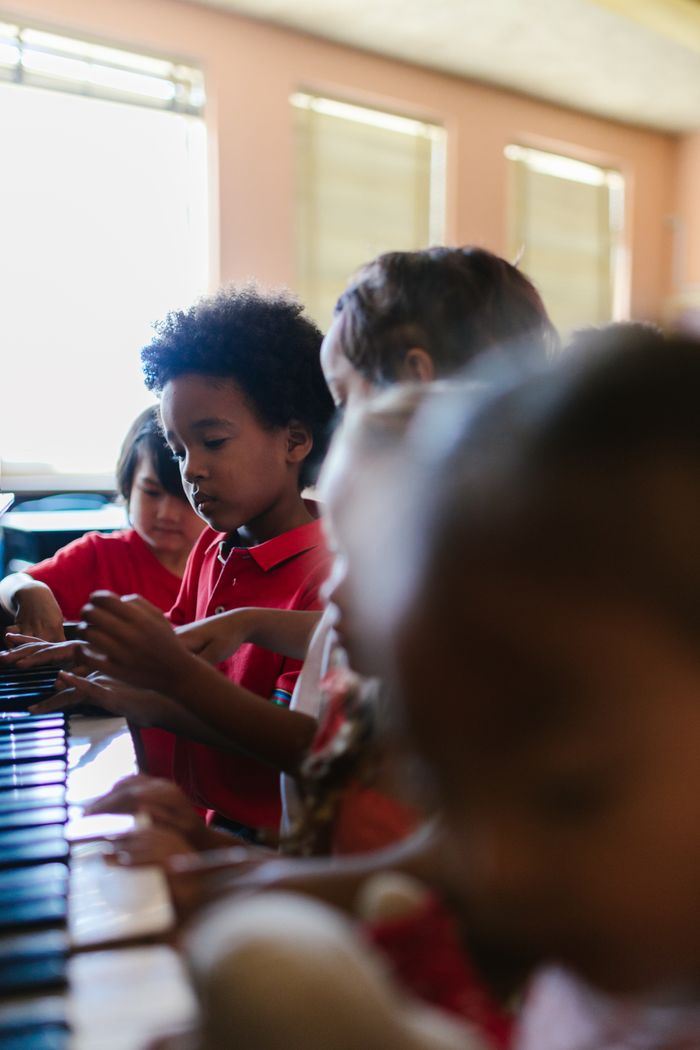 A group of elementary school children learning piano together in a classroom