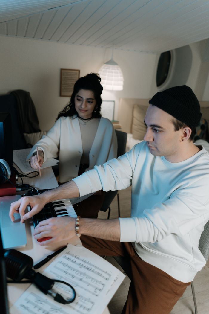 Two young musicians composing together at a keyboard with sheet music